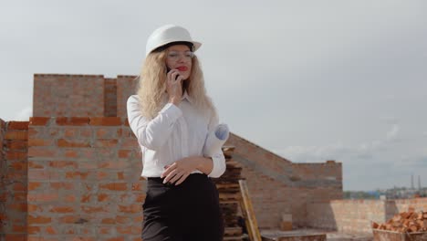 female architect in business attire stands in a newly built house and talking on the phone. modern technologies in the oldest professions