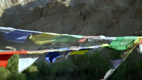 colorful prayer flags blowing in the wind in a mountainous outdoor setting - slow motion pan across vivid multi coloured tibetan buddhist flags flying in remote himalayas region of ladakh