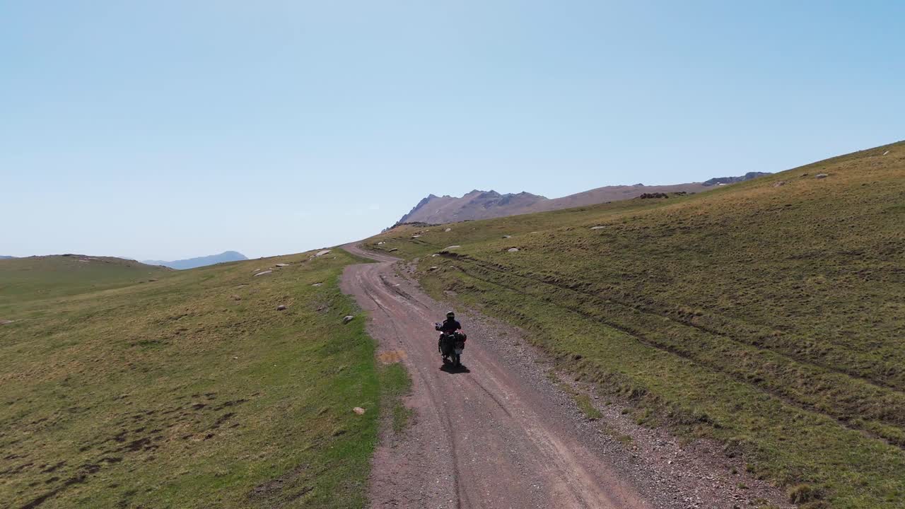 Drone follows a motorcycle rider driving in a wild off road plateau Path, Aerial landscape view