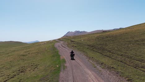 drone follows a motorcycle rider driving in a wild off road plateau path, aerial landscape view