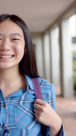 vertical video: in highschool, young asian female student is smiling