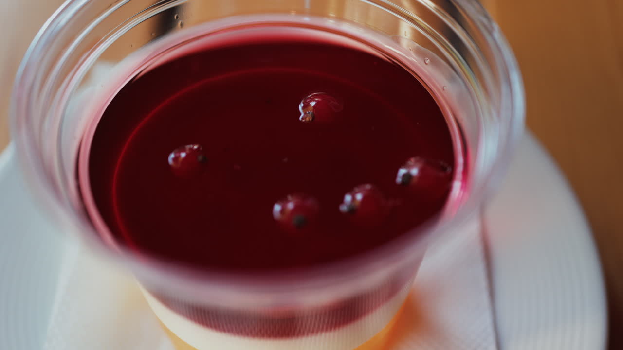 Close up of a bright layered jelly dessert in a clear cup on a wooden table