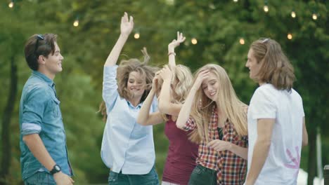 happy friends dancing, having fun and enjoying party outdoors.