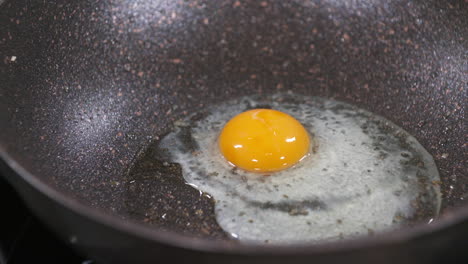 romper un huevo, hacer huevo frito en una sartén negra, huevos fritos, yema de huevo y clara de huevo