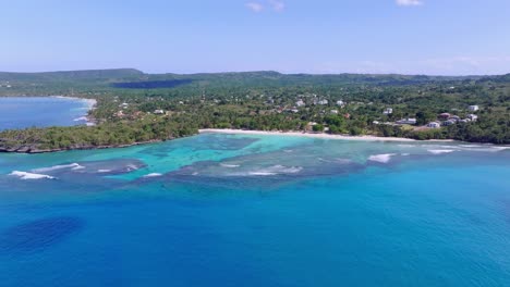 drone flying over blue sea with playa la playita beach in background, las galeras landscape in samana peninsula, dominican republic