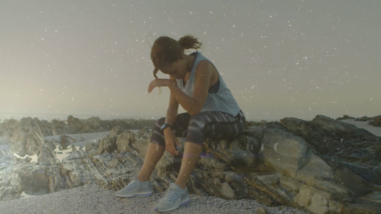 Atleta donna che fissa la costa rocciosa all'alba, affaticata con indicatore di fitness animato