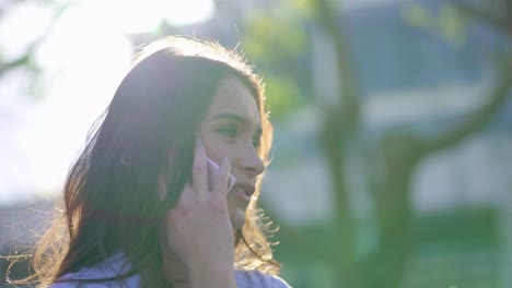 closeup of caucasian woman in park talking on phone, smiling