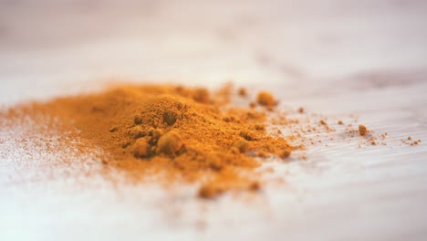 close shot of a pile of turmeric on a wooden surface spinning into focus from left