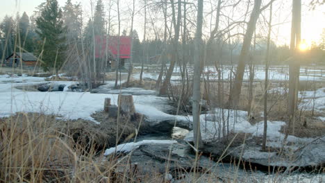 sunrise over small frozen farm with a flowing creek and red barn