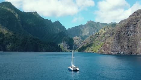 Toma-De-Seguimiento-De-Un-Catamarán-De-Vela-Que-Se-Dirige-Hacia-La-Bahía-De-Las-Vírgenes-En-Las-Islas-Fatu-Hiva-Marquesas-En-La-Polinesia-Francesa-En-El-Océano-Pacífico-Sur.