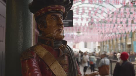 Mostrar-La-Figura-Del-Soldado-Fuera-De-Las-Tiendas-En-El-Mercado-De-Covent-Garden-Con-Turistas-En-Londres,-Reino-Unido