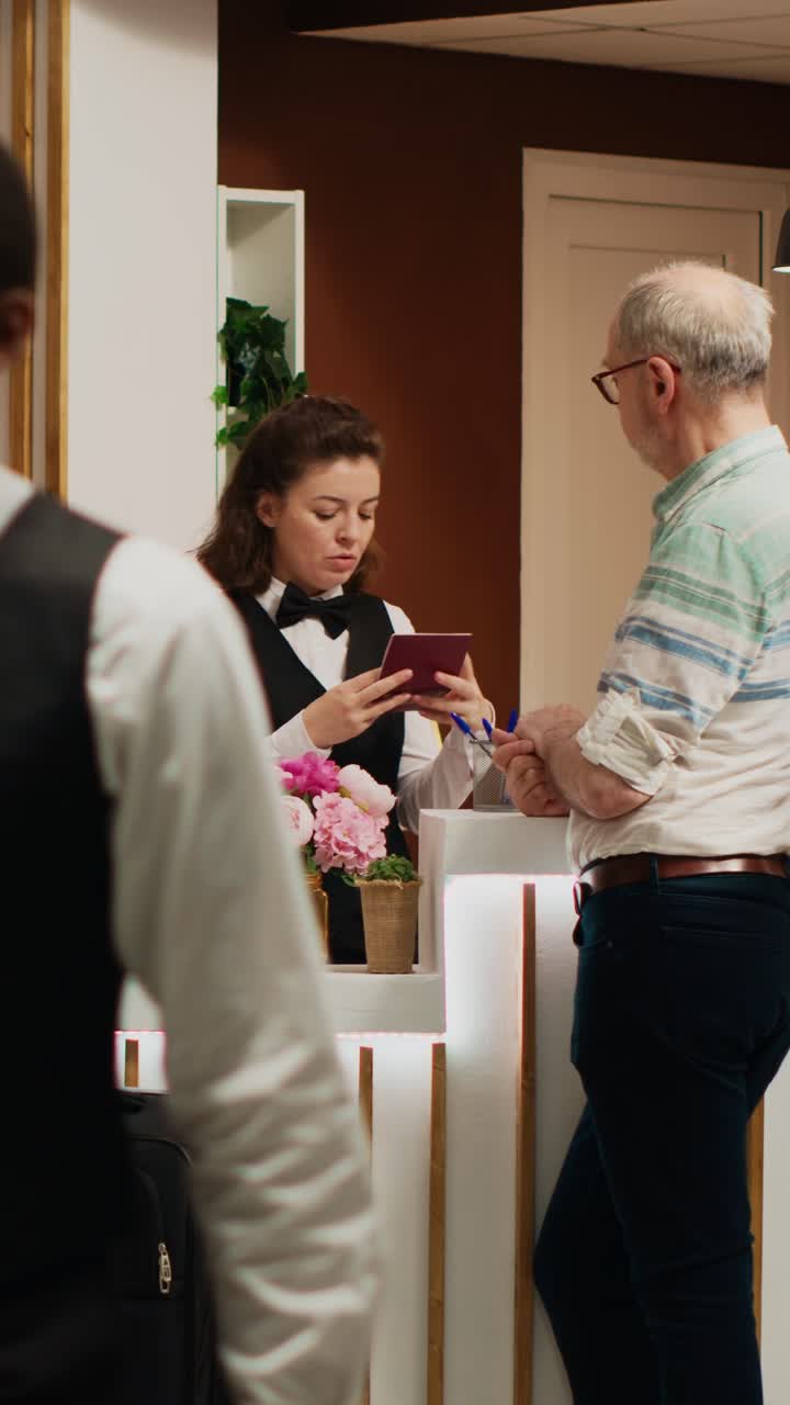 Video verticale: concierge d'hotel che esamina il passaporto