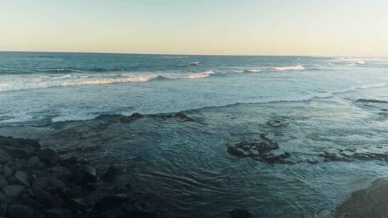 Onde serali si estendono lungo una costa rocciosa caraibica a Porto Rico.