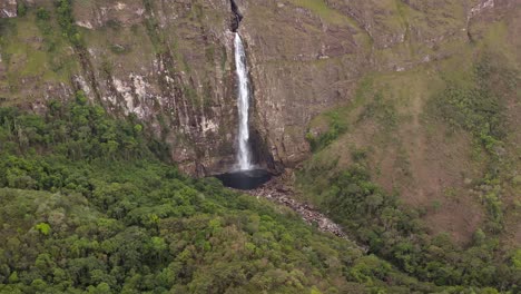 tall waterfall flowing into a natural pool in serra da canastra, brazil, aerial view