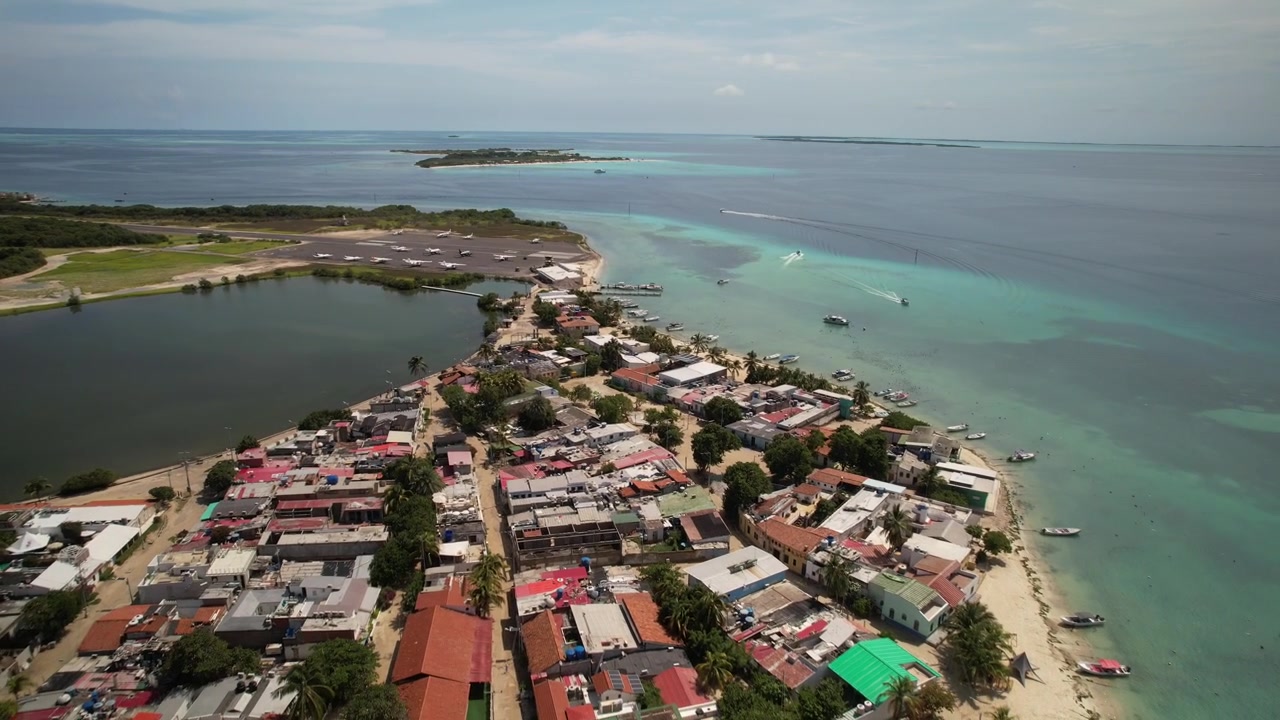 Isola di Gran Roque con acque turchesi, barche e un colorato villaggio costiero di giorno, vista aerea
