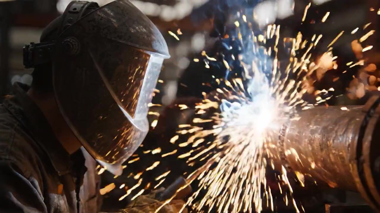 Skilled Welder at Work Creating Sparks While Joining Metal Parts in a Workshop, Showcasing the Intensity and Focus of the Craft in a Dynamic Industrial Setting