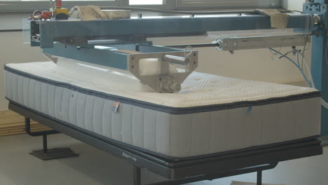 Heavy-roller-rolling-over-mattress-in-testing-facility---close