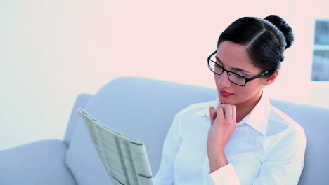 Attractive-businesswoman-sitting-on-couch-and-reading-newspaper