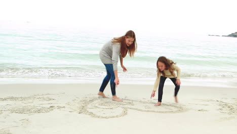 mother and daughter drawing on the sand