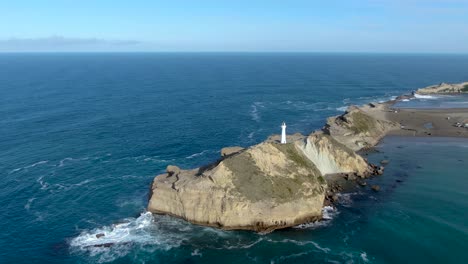 castlepoint lighthouse tower on rocky coast of north island, new zealand - aerial approaching view