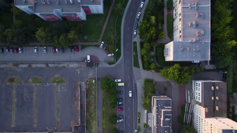 Toma-Aérea-De-Arriba-Hacia-Abajo-De-La-Conducción-De-Automóviles-En-La-Carretera-Entre-La-Zona-Residencial-Con-El-Complejo-De-Bloques-En-Cracovia