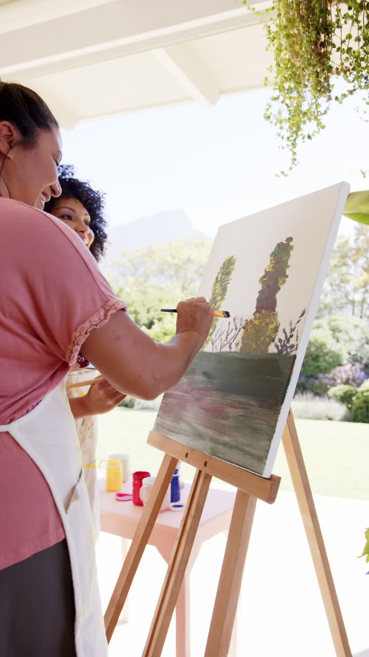 Vertical video: Enjoying outdoor art activity, women painting on canvas together