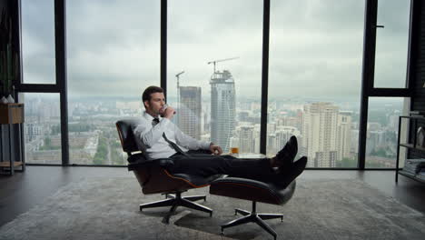 businessman sitting on chair in office interior. business man drinking scotch