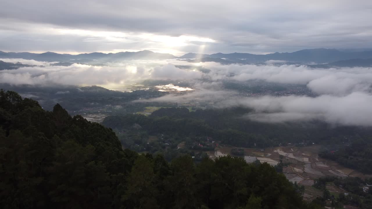 Sunrise over a misty valley with mountains and agricultural fields