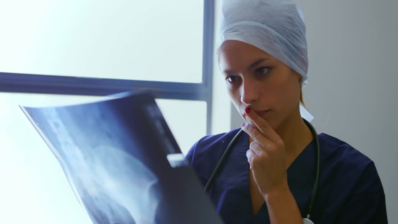 Medico solleva pellicola radiografica, ruotandola verso la finestra e scansionandola tramite sovrapposizione olografica per la diagnosi.