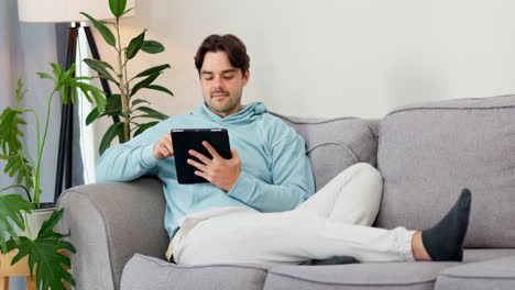 Man,-typing-and-relax-with-tablet-on-sofa-to-watch