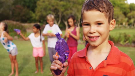 Portrait-of-smiling-boy-holding-a-water-gun