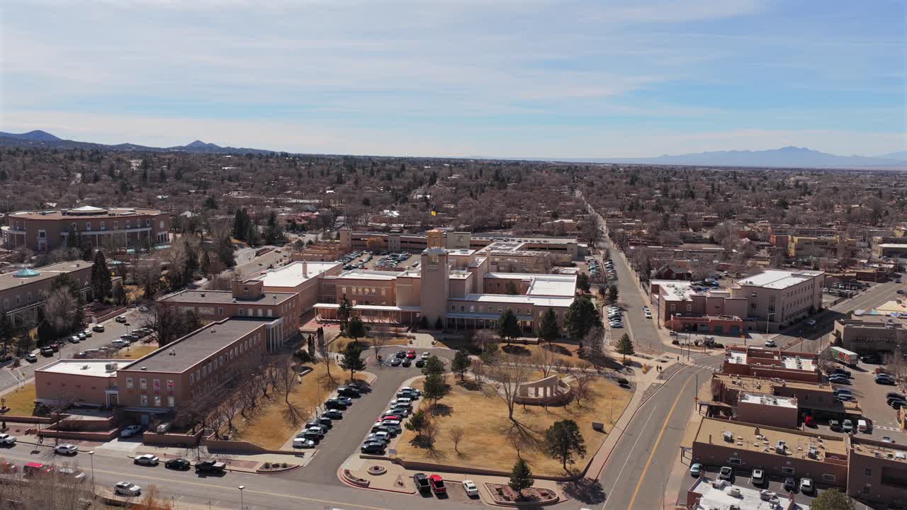 Un movimento laterale del drone cattura una vista distante dell'edificio circolare Roundhouse. Questa ripresa 4K mostra l'architettura unica in stile adobe del centro di Santa Fe contro il cielo del deserto.