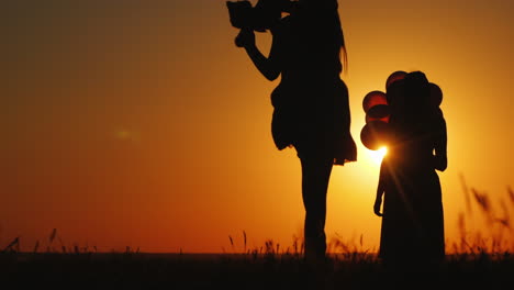 A-Child-Runs-To-His-Mom-Against-The-Backdrop-Of-A-Beautiful-Landscape-At-Sunset