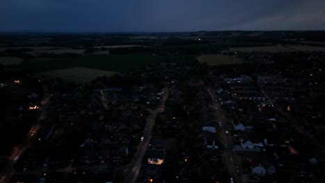 night scene in charming small town of america. dark blue sky after sunset. lighting buildings and streets in the evening. drone wide shot. hills and farm fields in distance. serene landscape in usa