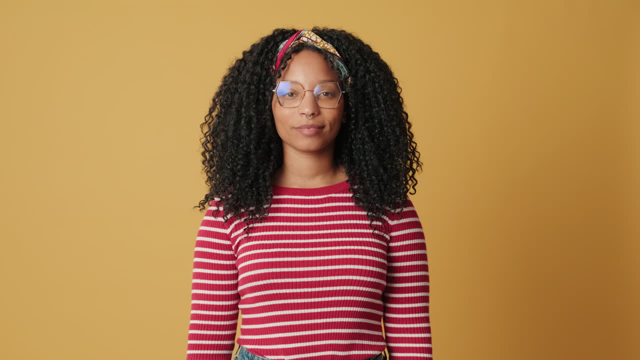 Young Woman with Curly Hair and Glasses Blinking in Studio