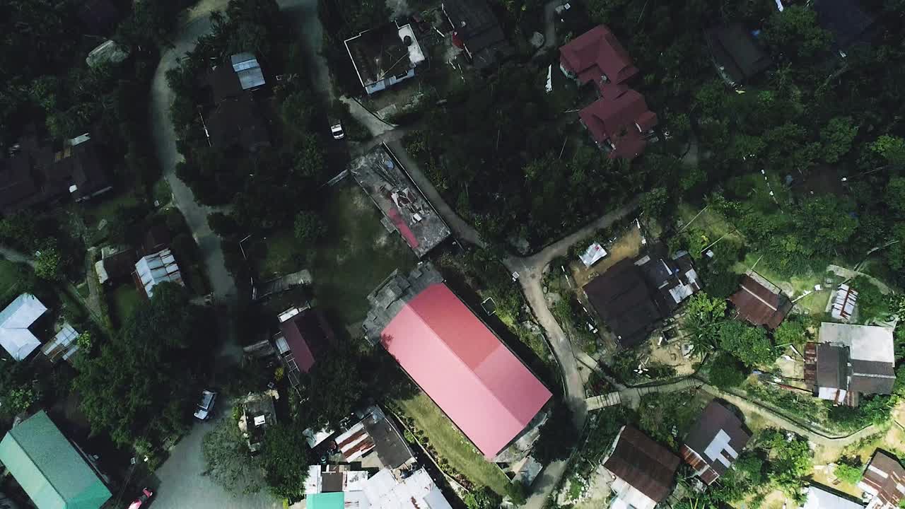 무성한 초목과 숲으로 둘러싸인 언덕 위에 지어진 마을 주택의 하향식 전망