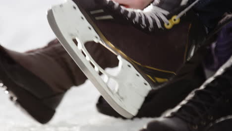 close shot poniéndose y atando patines para hielo al aire libre en la nieve.