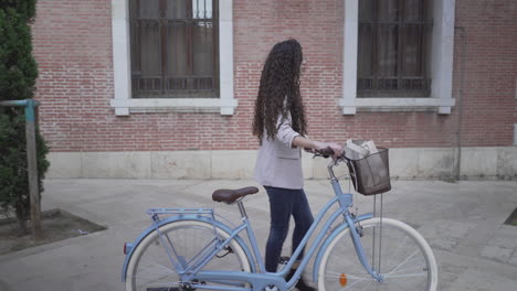 woman walking with bicycle in city street