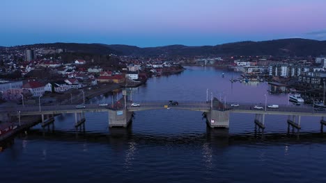 Porsgrunn-Stadtbrücke-–-Luftaufnahme-Am-Späten-Abend,-Die-Den-Verkehr-An-Der-Ove-Kanal-Brücke-Im-Morgengrauen-Zeigt-–-Ruhiges-Wasser-Im-Kanal-Unten-Und-Klarer-Himmel