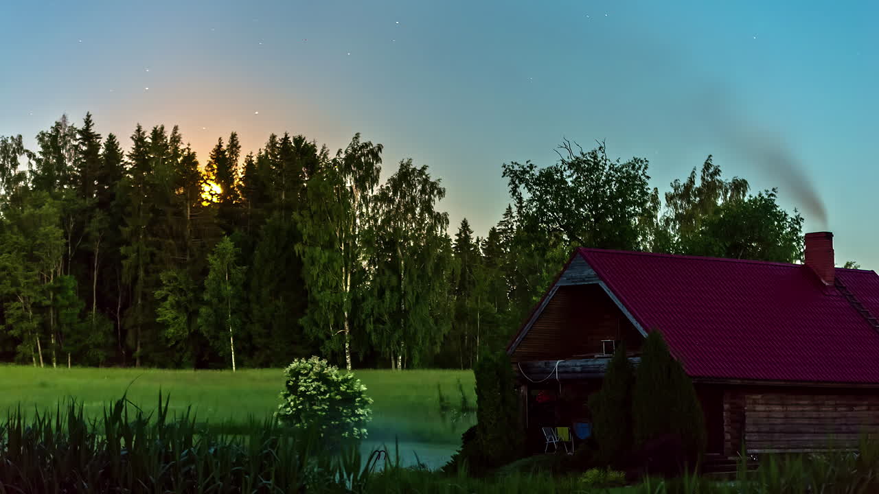 Time lapse of sun's descent behind forest near idyllic cabin in woods