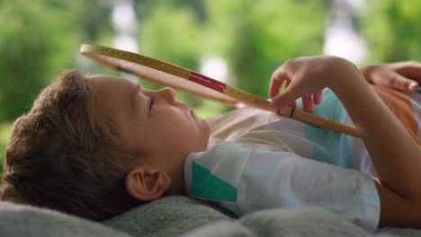 Closeup-racket-falling-down-on-boy-face.-Cute-child-lying-on-picnic-blanket.