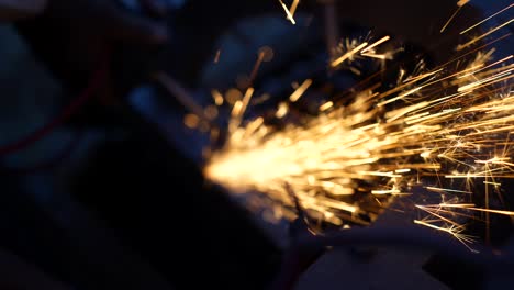 grinding metal with sparks flying. micro sparks light and yellow rays sparkling on heavy industry workshop.