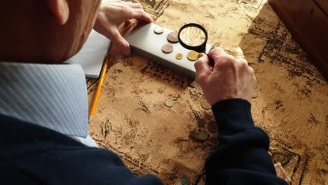 coin evaluator. the collector of coins. the man considers ancient coins.