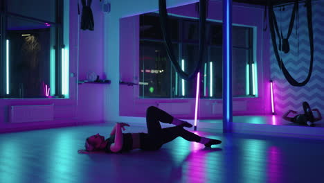 a woman dances in a studio with a neon light performing graceful exercises and movements from stretching and dancing in slow motion