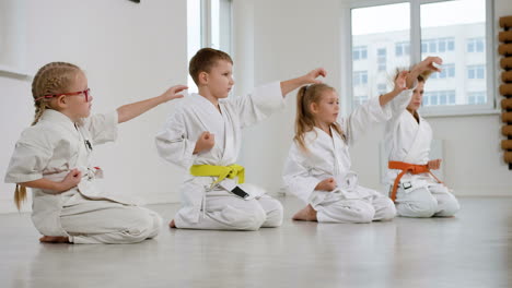 niños arrodillados en el suelo en la clase de artes marciales