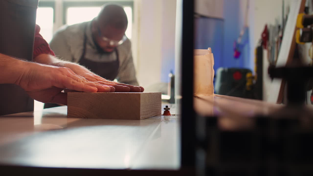 hombre poniendo bloque de madera a través de moldeador de huso, creando bordes lisos