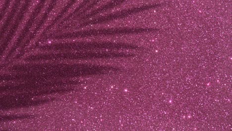 shadows from a palm tree on a pink glitter sparkling shining background. minimal art, glamor, vacation, summer, party concept.