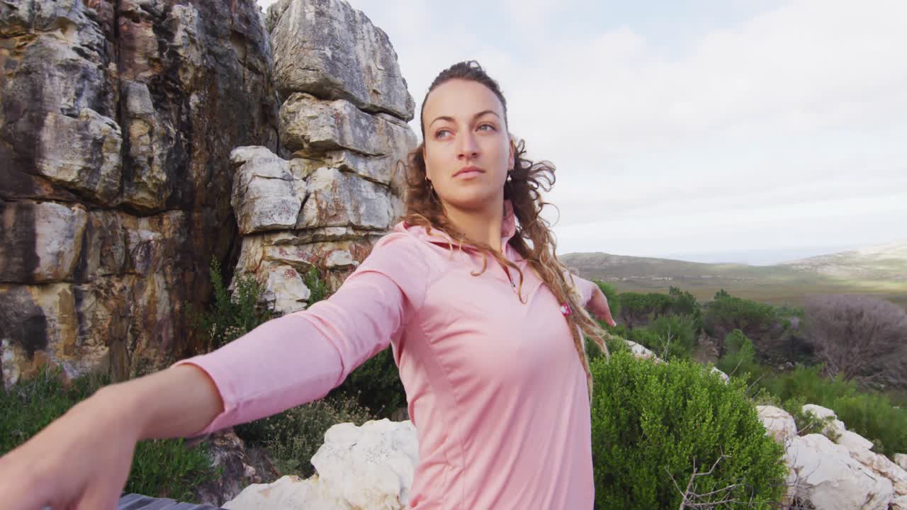 mujer caucásica practicando yoga al aire libre de pie en la cubierta estirándose en un entorno montañoso rural