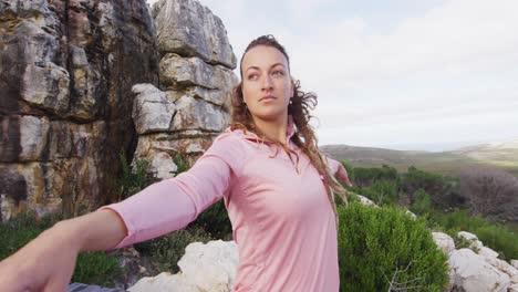 caucasian woman practicing yoga outdoors standing on deck stretching in rural mountainside setting