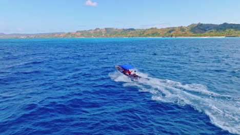 Tourists-on-motorboat-sailing-in-blue-Caribbean-sea-with-Samana-coast-in-background